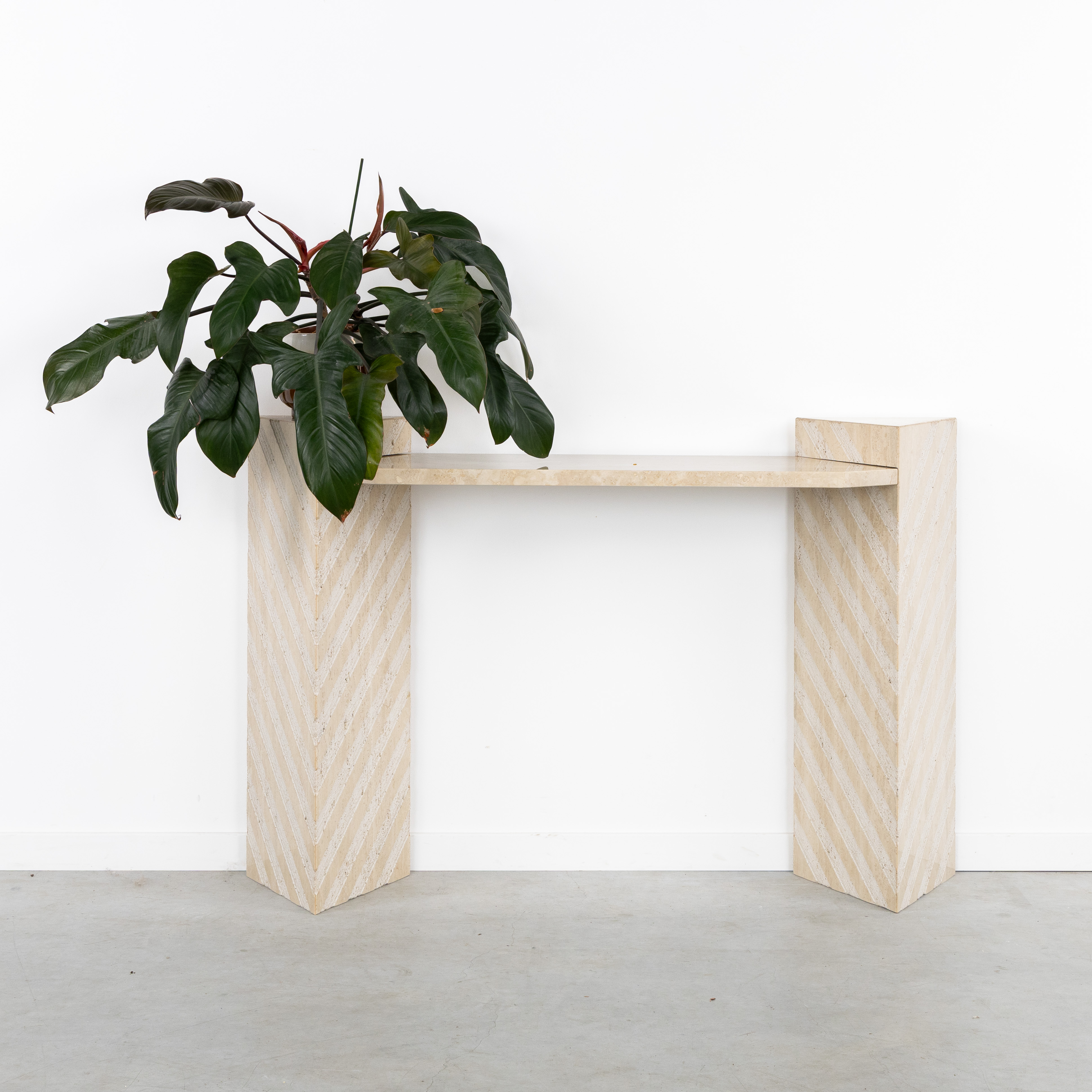 Een muurconsole of consoletafel, met geometrisch decor, travertin, circa 1980-1990. (L:125 x W:33 x H:85 cm)